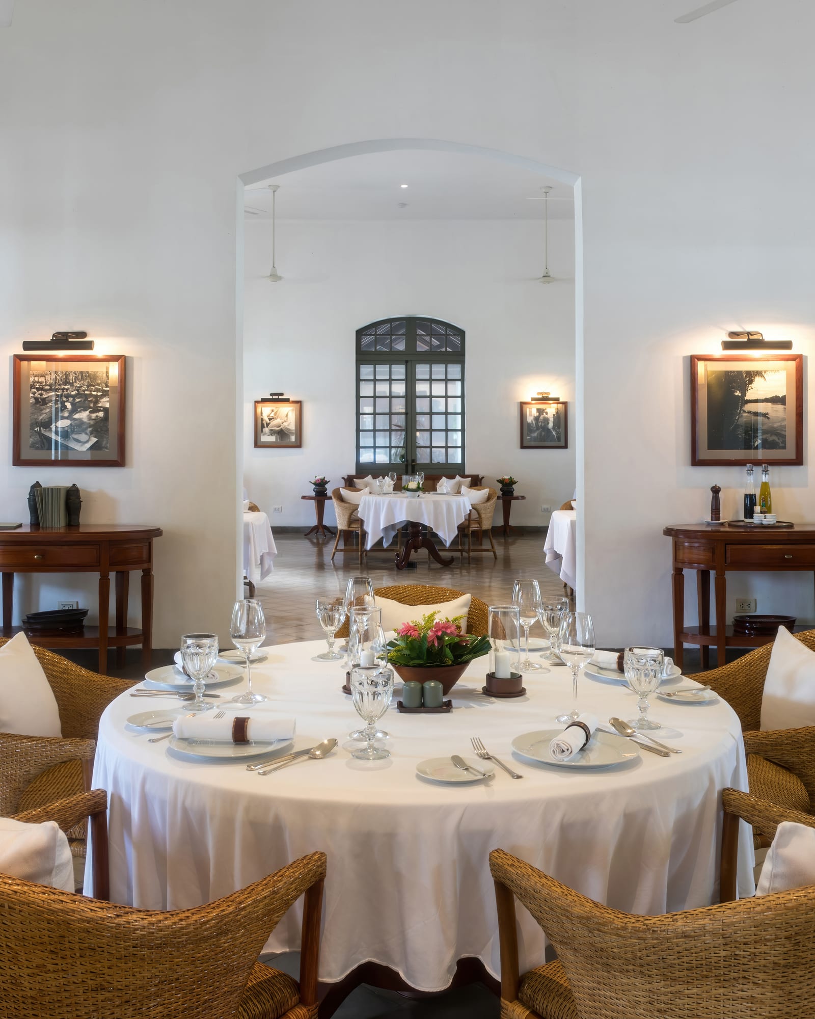 A set round dining table with wicker chairs in a bright, airy restaurant dining room.