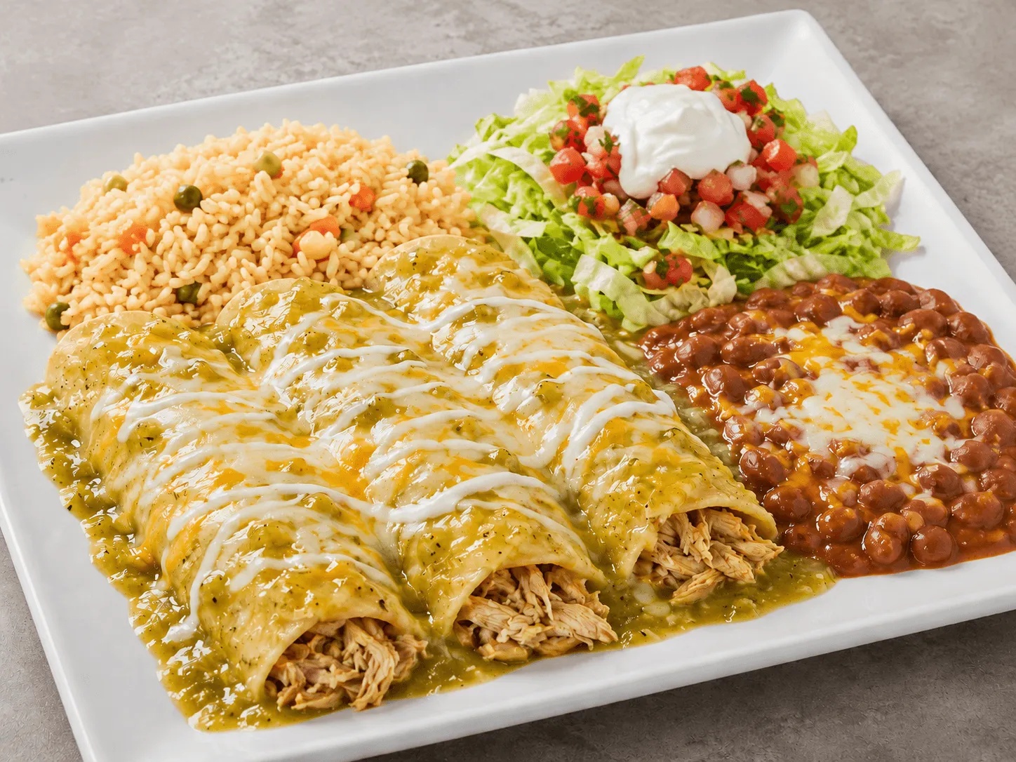 Green Enchiladas smothered with sauce, topped with mixed cheese and sour cream